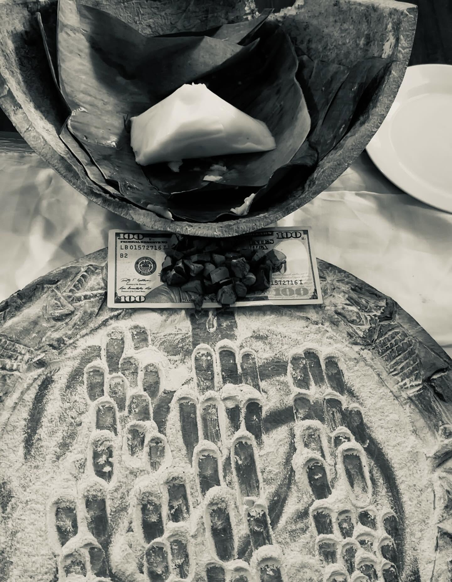 Ofrenda envuelta en hoja sobre el ọpọ́n tallado con obì y efun